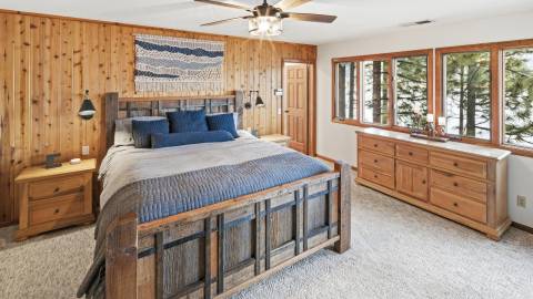 A photo of a Destination Big Bear cabin - there is a large comfy bed, a dresser & nightstand, and windows.