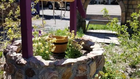 A photo of the entrance to Castle Wood Cottages - there is a wishing well and a castle arch wall.