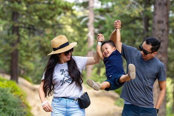 A photo of a family hiking as they playfully raise their child up.