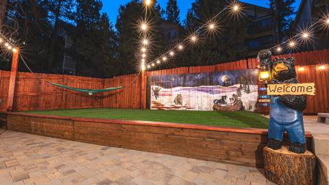 A photo of Winterland Cabins - there is a statue of a bear, it is holding a "welcome" sign.