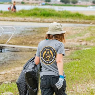 A volunteer wears a Care For Big Bear t-shirt and carries trash bag to fill during a clean up event.