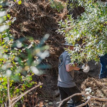 Volunteers clear away trash from a creek bed during a Care For Big Bear clean up event.