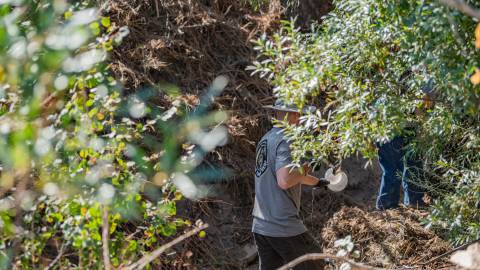 Volunteers clear away trash from a creek bed during a Care For Big Bear clean up event.