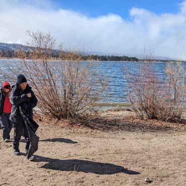A pair of warmly bundled volunteers scanning the Big Bear Lakeside for any trash to clean up as efforts to Care For Big Bear.