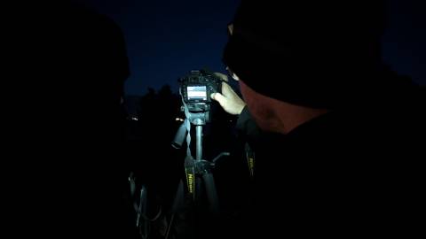 A professional night time photography, Brady Enger, showing an observer how to operate a camera for night sky photography.
