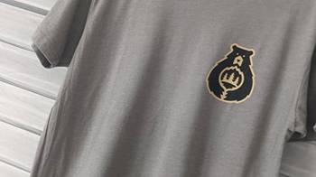 A gray T-shirt with the Care For Big Bear Logo being displayed, the shirt is on a clothes display