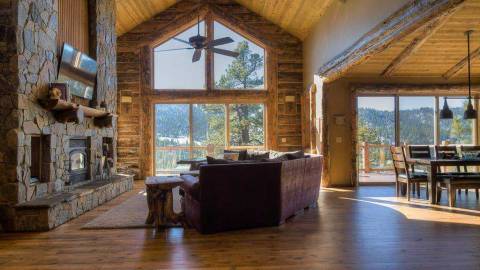 A photo of a wooden cabin by Nena's Nook - the mountains and trees are visible in the distance through the large windows.