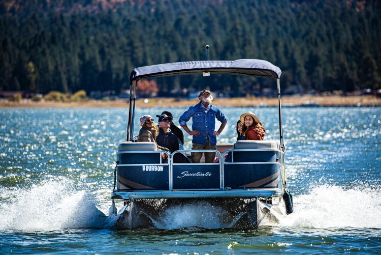 A group of tourists smile on a pontoon boat ride across Big Bear Lake