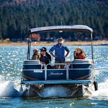 A group of tourists smile on a pontoon boat ride across Big Bear Lake