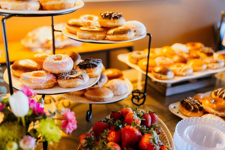 A buffet spread for Mothers Day - there are different types of donuts ranging from chocolate, caramel, and sugar.