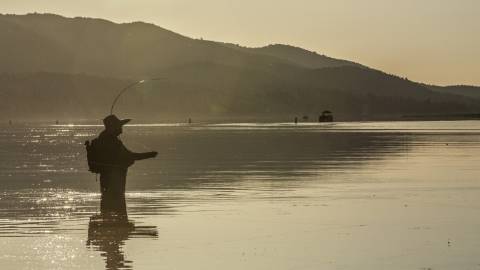 A wading angler patiently awaits his catch big bear lake