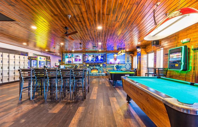 A photo of the Alley Oops Sports Bar at The Bowling Barn - there are three large TVs, a music selector, and a pool table.