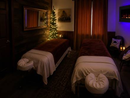 Two long massage tables in a room gently illuminated by mood lighting - the massage tables have plush covers and headrests.