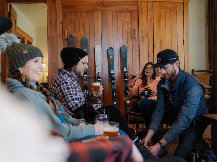 A photo of a male relaxing on a couch in his cabin while getting a Ski Shoe fitting by Ski Butlers.