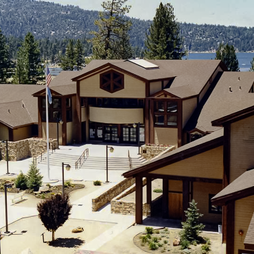 An aerial image of Big Bear Lake City Hall. The blue lake and green forest are visible in the background.
