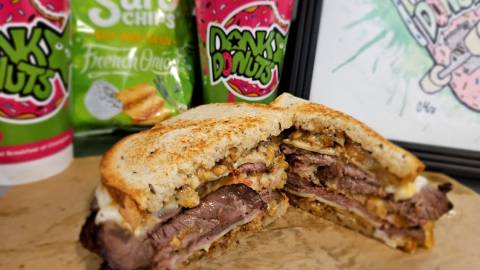 A cross-section photo of Dank Donut's hot sandwich "The Lockness Muenster" - there are hot drinks in the background.