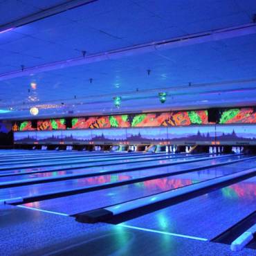 Blue neon lights illuminate the lanes indoors at the Big Bear Bowling Barn during glow bowling events.
