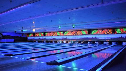 Blue neon lights illuminate the lanes indoors at the Big Bear Bowling Barn during glow bowling events.