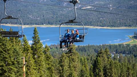 A family of three enjoying a ride on the Sky Chair overlooking the beautiful Big Bear Lake and the valley in the background.