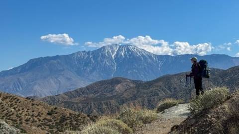 A photo of a hiker overlooking the Big Bear Valley, the snow topped mountains visible in the distance.