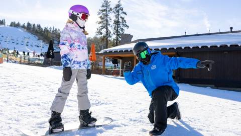 An instructor guides a student on a snowboard at Snow Summit ski resort in Big Bear Lake, CA.