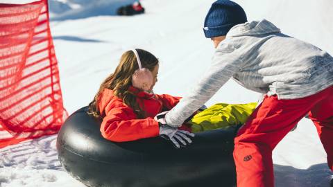 One child pushes a friend on a snow tube during snow play in Big Bear Lake, CA.