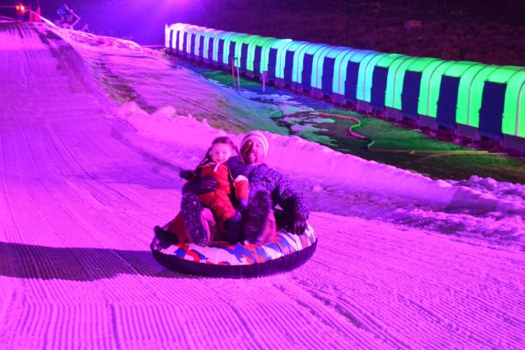 A parent and child slide down the tubing hill during Glow Tubing in Big Bear Lake.