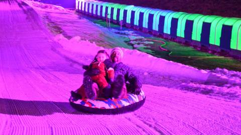 A parent and child slide down the tubing hill during Glow Tubing in Big Bear Lake.