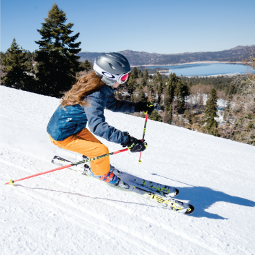A photo of a skier going down the snow covered slopes at Bear Mountain - the mirror like lake water visible in the distance.