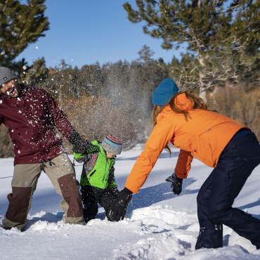 A family of three play in the snow during winter in Big Bear Lake.