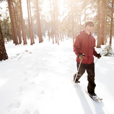 A man snowshoes in a winter forest in Big Bear Lake.