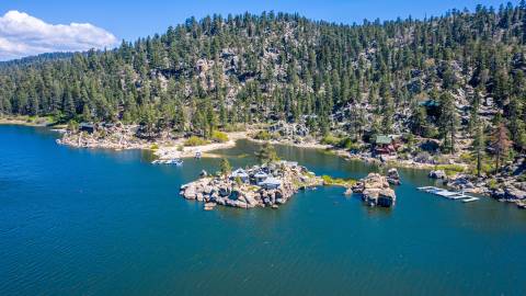An aerial view of Big Bear Lake. Garstin Island is in the foreground and the forested shoreline sits in the background.