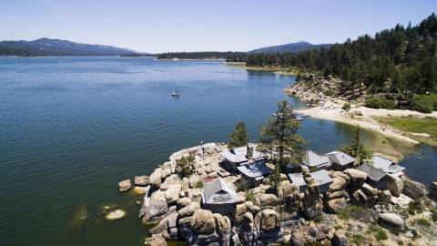 A Chinese style home sits on a rock island in Big Bear Lake. It's a sunny day with blue skies.