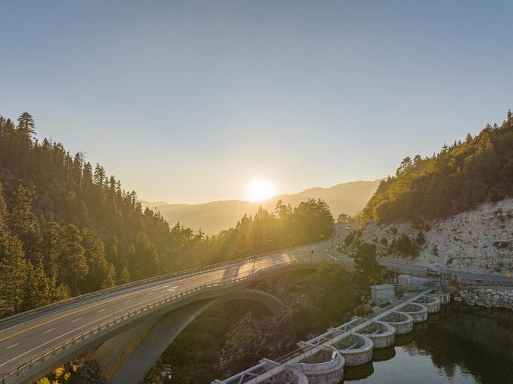 The sun sets over the Big Bear Dam and road bridge in the fall season.