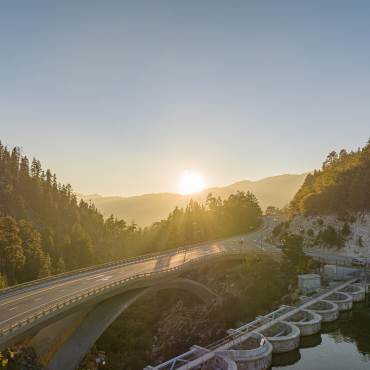 The sun sets over the Big Bear Dam and road bridge in the fall season.