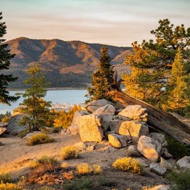 A view of Big Bear Lake through the trees from the Castle Rock hiking trail in the Fall Season. It is sunset.