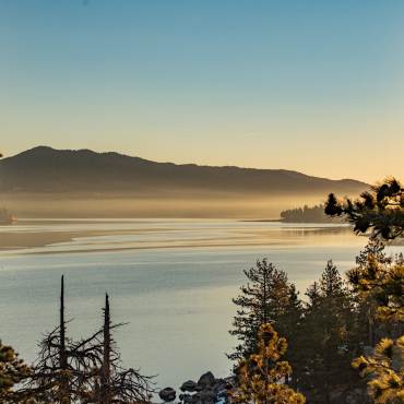 A photo taken during a golden hour in Big Bear Lake, the fog and lake water gently reflecting the gold-ish light.