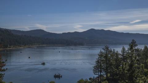 A photo of the Big Bear Lake, there are many boats out on the water, the trees and mountains are visible in the distance.