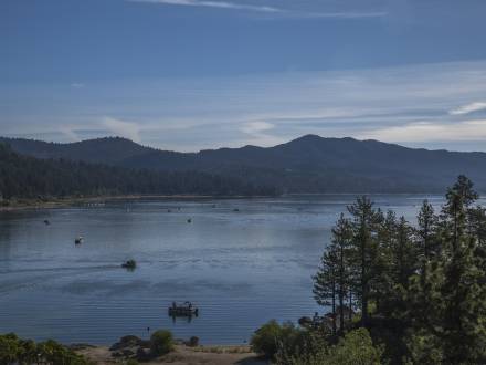 A photo of the Big Bear Lake, there are many boats out on the water, the trees and mountains are visible in the distance.