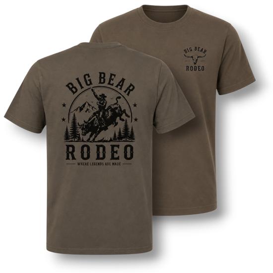 A pine colored t-shirt sold during the Big Bear Lake Rodeo - the back has a cowboy riding on top of a bull.