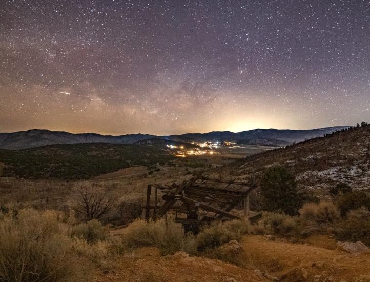An image of the stars and Milky Way galaxy in the night sky over Big Bear. An old mining shaft sits in the foreground.