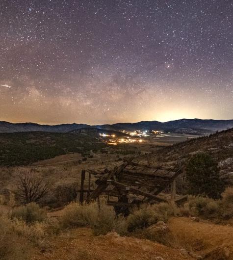 An image of the stars and Milky Way galaxy in the night sky over Big Bear. An old mining shaft sits in the foreground.