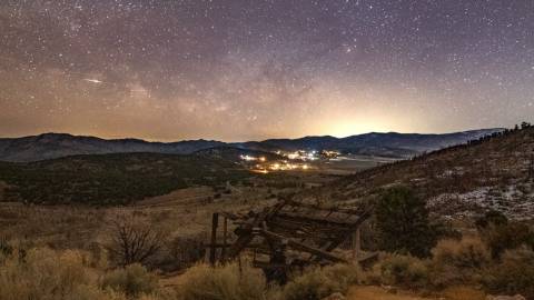 An image of the stars and Milky Way galaxy in the night sky over Big Bear. An old mining shaft sits in the foreground.