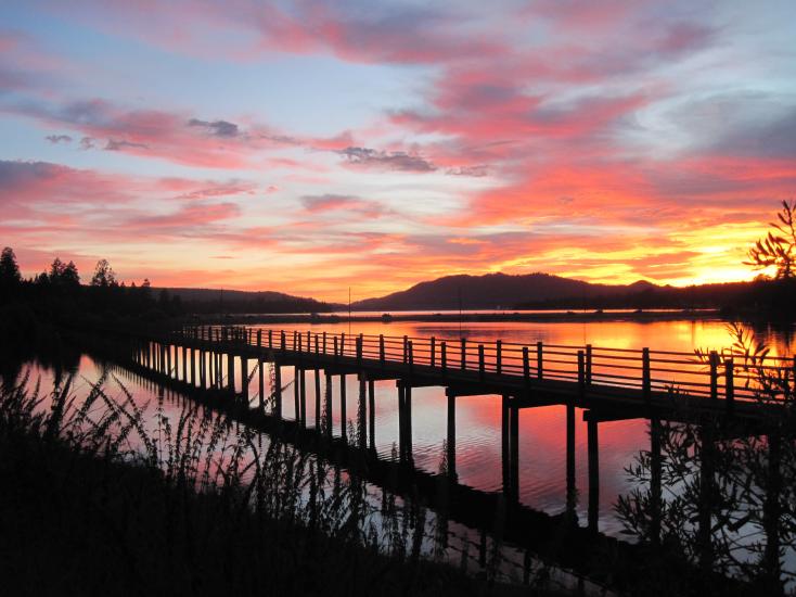 A colorful sunset in Big Bear Lake with reds, purples, and yellows in the sky over a black silhouette of the Boardwalk.
