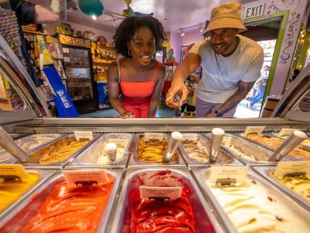 A couple peers through glass at a selection of colorful gelato flavors at a sweet shop in The Village at Big Bear Lake, CA.