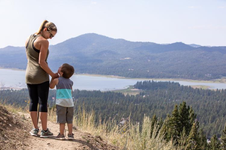 A photo of a mother and son on a hiking trail overlooking the Big Bear Valley, the lake and mountains visible in the distance