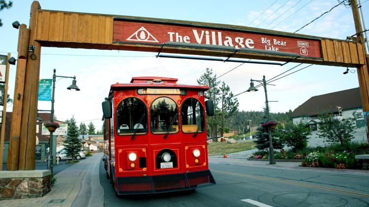 The Mountain Trolley driving underneath Big Bear's "The Village Sign"