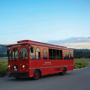 a red Mountain Transit trolley transports riders through Big Bear Lake