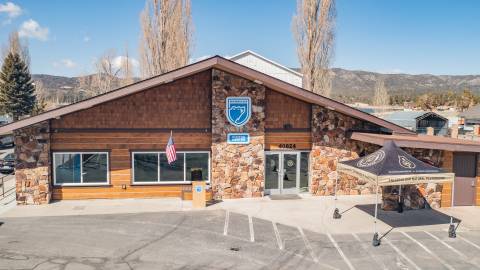 The Big Bear Lake Visitor Center front facing facade in the summer season. The blue bear logo is features among natural stone