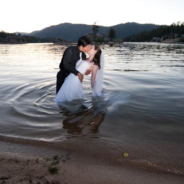 A bride and groom share a kiss during their wedding ceremony while wading in Big Bear Lake.